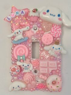 a pink and white phone case with lots of different items on the front, including a house