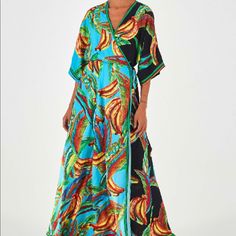 1/2 Sleeve Mixed Print Maxi Wrap Dress. V Neckline. Kimono Sleeves. Side Tie Closure. Decorative Trim Around Neckline And Hems. Composition 100% Viscose Care Instructions Machine Wash, Gentle Cycle; Do Not Bleach; Tumble Dry, Low; Iron Warm; Dry Clean Only Blue V-neck Wrap Dress For The Beach, Blue V-neck Wrap Dress For Beach, Blue Maxi Length Wrap Dress For Vacation, Blue Maxi Wrap Dress For Vacation, Chic Blue Maxi Dress With Vibrant Print, Short Sleeve Blue Wrap Dress For Vacation, Blue Floral Print Maxi Wrap Dress, Blue Short Sleeve Wrap Dress For Vacation, Tropical Blue Maxi Dress For Beach