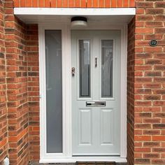 a white front door with glass panels and sidelights on a brick house in england