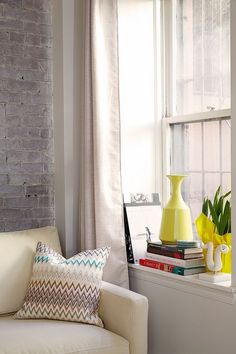 a white couch sitting next to a window filled with books and vases on top of it