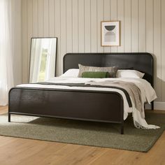 a bed sitting on top of a wooden floor next to a white and green rug