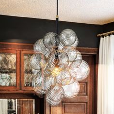 a chandelier hanging from the ceiling over a dining room table in front of a wooden cabinet