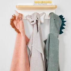 three towels are hanging on the wall next to a book shelf with two stuffed animals