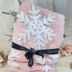 two pink towels with white snowflakes on them and black ribbon around the edges