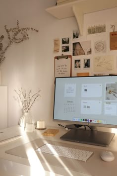 a desktop computer sitting on top of a desk next to a vase with flowers in it