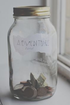 a jar filled with money sitting on top of a window sill