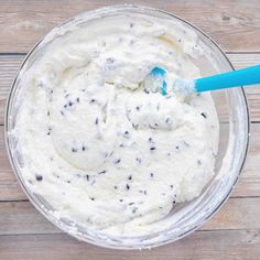 a glass bowl filled with cream and chocolate chip cookie dough on top of a wooden table