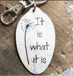 a dandelion keychain with the words it is what it is on it