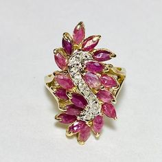 14K Yellow Gold Marquise Cut Ruby Diamond Cocktail Ring Size 9 18 Marquise cut rubies, measuring approx. 5 x 3 mm, 4.50ctw 10 Round brilliant cut diamonds, measuring approx. 1.0 mm, 0.05ctw Approx. top measurements: length 16.0 x width 29.3 x height 11.3 mm Shank measures 2.3-2.1 mm Stamped R 14K (stamp is worn and not clear in photo, we electric tested as 14k gold) Total weight approx. 7.34 g Condition preowned, please see photos for details Ruby Butterfly Ring, Pink Cluster Jewelry With Diamond Accents, Cluster Ruby Diamond Ring, Cluster Ruby Ring Fine Jewelry, Multi-stone Cluster Ruby Ring, Multi-stone Ruby Cluster Ring, Marquise Ruby Jewelry With 17 Jewels, Cluster Ruby Ring With Diamond Accents, Marquise Ruby Ring Fine Jewelry