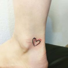 a small tattoo on the ankle of a woman's foot with a heart in it