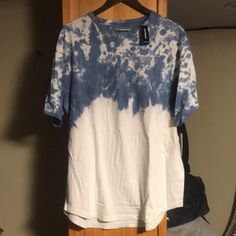 a blue and white tie dye shirt hanging on a wooden hanger in front of a mirror