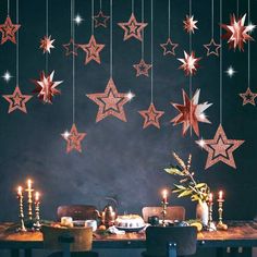 a dining room table with candles and stars hanging from the ceiling