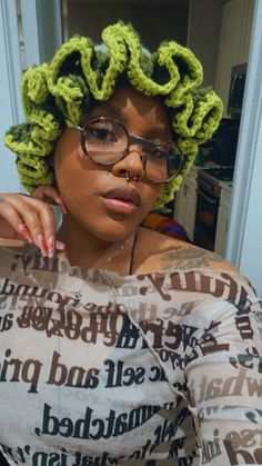 a woman wearing glasses and a green crochet wig with her hands on her shoulder