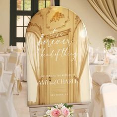 a wedding sign with flowers on it in the middle of a room filled with tables and chairs