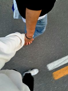 two people holding hands while walking down the street