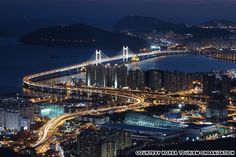 an aerial view of a city at night with the bay bridge in the foreground