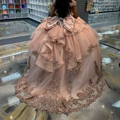 a woman in a pink dress is looking down at the floor and she has her back to the camera