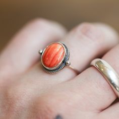 Sometimes you want to gaze down at your ring and see perfect balance and grace. That's what the Delica Dainty Ring has to offer. High-grade Spiny Oyster Shell Ring with a simple, sterling silver design. Perfect little ring. Lovely, traditional, dainty ring of 10X12 mm Spiny Oyster cabochon set in .925 sterling silver - oxidized and burnished bezel and wire. Simple, elegant and perfect. This lovely little orange-red ring is created using traditional silversmithing techniques in my Baltimore, MD s Heirloom Oval Stackable Jewelry, Untreated Oval Ring Fine Jewelry, Untreated Oval Rings Fine Jewelry, Untreated Oval Ring In Fine Jewelry Style, Adjustable Oval Rings With Ethical Gemstones, Unique Untreated Ring Jewelry, Untreated Round Band Jewelry As Gift, Untreated Round Band Jewelry Gift, Adjustable Oval Spiritual Rings