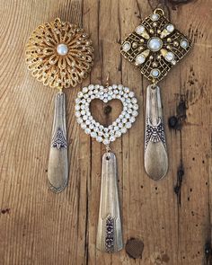 three spoons and two brooches on a wooden table