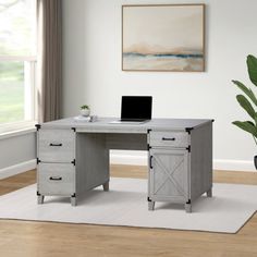 a desk with a laptop on it in front of a potted plant and window