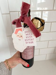 someone holding up a wine bottle with some stickers on it and a santa hat