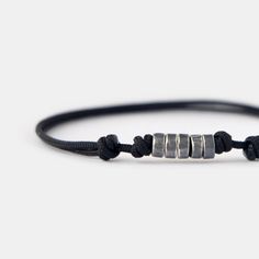 This men's beaded bracelet effortlessly combines a minimalist design with a touch of sophistication and masculinity, creating a captivating and unique piece. The combination of oxidizing surface and texture of handmade silver beads on the black cord catches the eye and adds a touch of personality to your style. With its lightweight and durable construction, this cord bracelet is designed for everyday wear. The adjustable cord ensures a comfortable and secure fit, making this minimalist bracelet a perfect accessory for your everyday adventures. D E T A I L S * 1.5 mm strong black nylon cord for comfortable everyday wear. * Oxidized sterling silver beads, approximately 5 mm. * Adjustable length with sliding knots. * Available in various sizes for a customized fit. * Designed in Barcelona. Al Everyday Silver Minimalist Wristband, Minimalist Silver Wristband For Everyday, Masculine Everyday Adjustable Bracelets, Minimalist Sliding Knot Bracelets, Modern Adjustable Wristband For Everyday, Modern Adjustable Wristband For Everyday Wear, Silver Minimalist Wristband, Minimalist Black Bracelet, Minimalist Black Jubilee Wristband