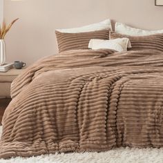 a bed with a brown comforter on top of it in a bedroom next to a white rug