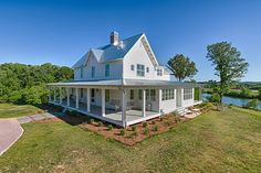 a large white house sitting on top of a lush green field next to a river