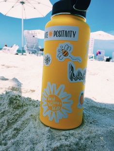 a yellow water bottle sitting on top of a sandy beach