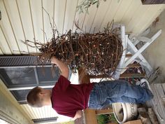 a young boy standing on a porch next to a house with christmas lights in it