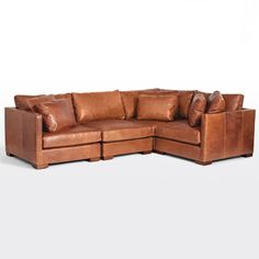 a brown leather sectional sofa with lots of pillows on the top and bottom corner, in front of a white background