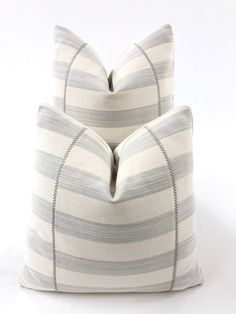 two gray and white striped pillows sitting on top of each other in front of a white background