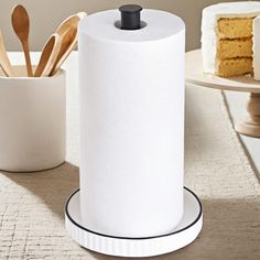 a roll of toilet paper sitting on top of a table next to a cup and cake