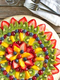 a fruit pizza with kiwis, strawberries, oranges and blueberries