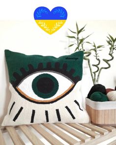 a pillow with an eye on it next to a potted plant and yarn ball