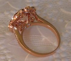 A beautiful and substantial engagement ring featuring a round peachy-pink untreated morganite center stone set in 14K rose gold elegant filigree ring. The center stone is a peachy-pink morganite, measuring about 9mm diameter (approximately 2.5 carats). It is cut in a Portuguese cut and very lively. The delicate peachy pink color of this morganite complements the rose gold very nicely. The morganite is set in an antique-inspired 14K rose gold filigree ring, featuring 0.16 carats of GH VS2 diamond Luxury Rose Gold Topaz Ring For Wedding, Rose Gold Flower Ring With Rose Cut Diamonds, Rose Gold Flower Ring With Prong Setting, Rose Gold Morganite Topaz Ring, Morganite Sapphire Ring With Halo Setting, Formal Rose Gold Topaz Ring With Halo Setting, Rose Gold Flower Ring With Center Stone, Morganite Diamond Wedding Ring, Formal Rose Gold Flower Ring With Center Stone