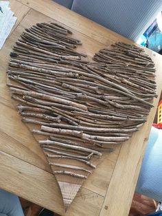 a heart made out of sticks sitting on top of a wooden table