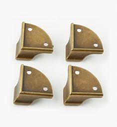 three brass plated metal brackets on a white background