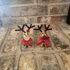 two wooden reindeer figurines with red bows on their heads are standing in front of a brick wall