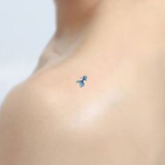 a small blue bird tattoo on the left side of a woman's chest,