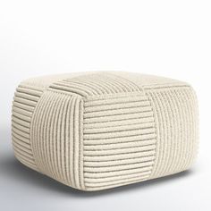 a white ottoman that is made out of yarn and has a square design on the top