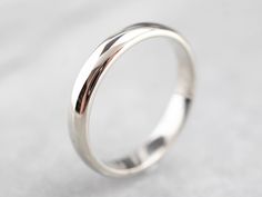 "Simple, clean lines make this band a classic choice! The band is low domed and proportionately wide which gives the band a contemporary feel. The curved comfort fit inside gives the ring a great feel on the finger. This is sized and designed in a unisex way, and will look great on a man or a woman's hand. Metal: 14K White Gold Width of Band: 3.0 mm Height off Finger: 1.3 mm Ring Size: 5.25 Marks: \"14K\" Stamped on the inside band SKU #: KC5DR7MR Each piece has been identified and graded by a G Timeless Wedding Bands With Polished Finish, Classic Rings With Shiny Round Band, Classic Rings With Shiny Finish And Round Band, Elegant Wedding Bands With Smooth Bezel, Wedding Band With Smooth Bezel, Wedding Rings With Smooth Finish And Round Band, Elegant Wedding Band With Smooth Finish, Modern White Gold Wedding Ring With Thick Band, Minimalist Wedding Bands With Smooth Finish