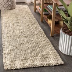 a living room with a rug on the floor next to a coffee table and potted plant