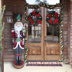 a large nutcracker statue sitting in front of a wooden door with wreaths on it