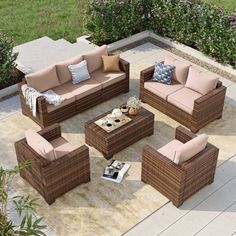 an outdoor living room with wicker furniture and pink cushions on the floor, surrounded by greenery