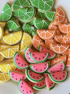 some decorated cookies are on a plate with lemons and watermelon slices in the background