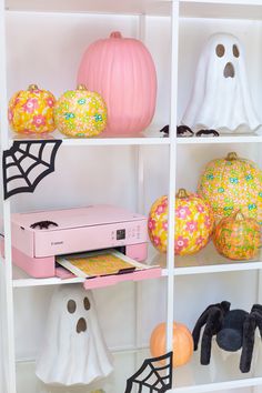 halloween decorations on shelves in a room with white walls and pumpkins behind the shelves