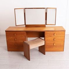 a wooden desk with two mirrors and a stool