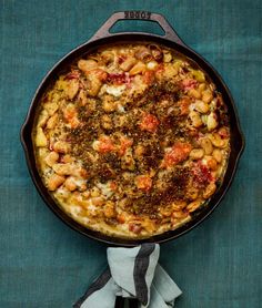 a pan filled with food sitting on top of a blue tablecloth next to a napkin