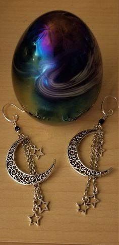 These bewitching earrings are super enchanting. Filigree crescent moons, with "shooting stars", suspended from varying lengths of chain. Atop each, is a  Jet colored 4mm Czech fire polished bead and it's finished off with a Sterling plated earring with a cute little curl, that complements the scrollwork in the moons. Dress it up or down. You can't go wrong. These dangles measure a stunning 3 3/4" long.  Since it's the season of giving, I'm including a gift box for these. Of course, they come with the rubber stoppers, to ensure they stay in. Star Chandelier, Season Of Giving, Galaxy Earrings, The Moon And Stars, Moon Jewelry, Moon And Stars, Shooting Stars, Chandelier Earrings, Crescent